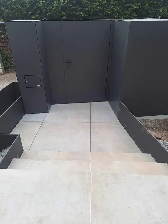 Neu gestalteter Außenbereich mit hellen Terrassenplatten und anthrazitfarbenen Wänden